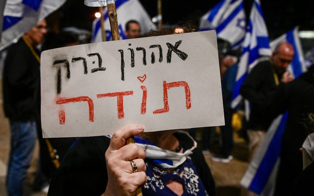 מפגינה אוחזת בשלט תמיכה באהרן ברק בהפגנה ליד ביתו בתל אביב, 20 באפריל 2023 (צילום: אבשלום ששוני, פלאש 90)