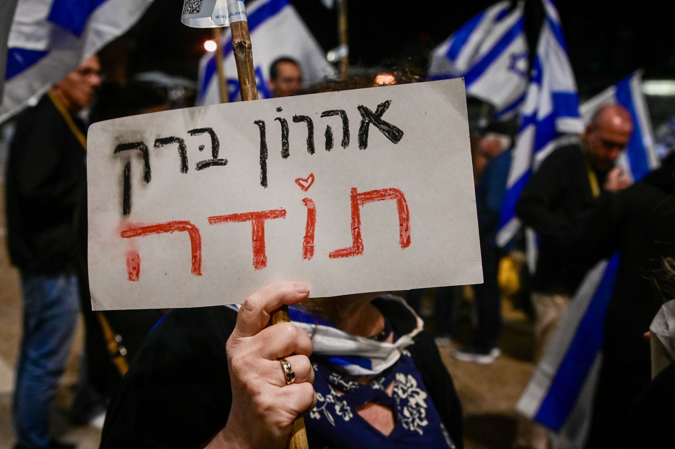 מפגינה אוחזת בשלט תמיכה באהרן ברק בהפגנה ליד ביתו בתל אביב, 20 באפריל 2023 (צילום: אבשלום ששוני, פלאש 90)