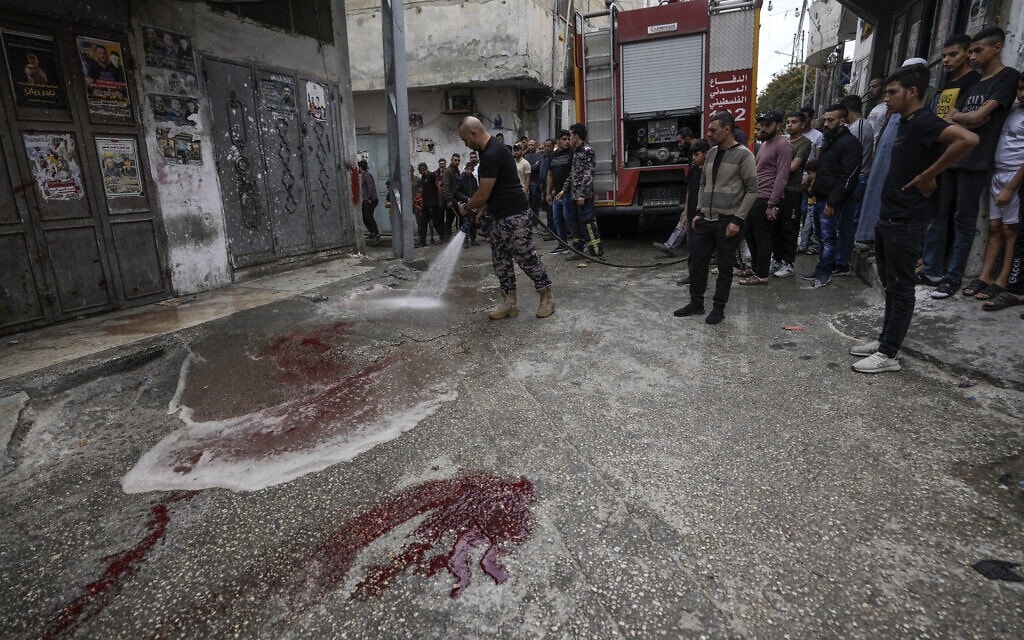 דמם של פלסטינים שנהרגו בהפצצה ישראלית נשטף מהכביש במחנה הפליטים בלטה, 13 במאי 2023 (צילום: Majdi Mohammed, AP)