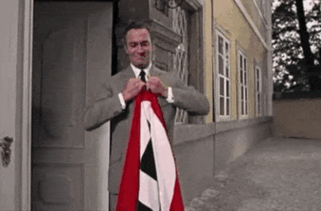 קפטן פון-טראפ (כריסטופר פלאמר) קורע את דגל הסווסטיקה שנתלה באחוזתו בסרט &#8220;צלילי המוזיקה&#8221;, 1965