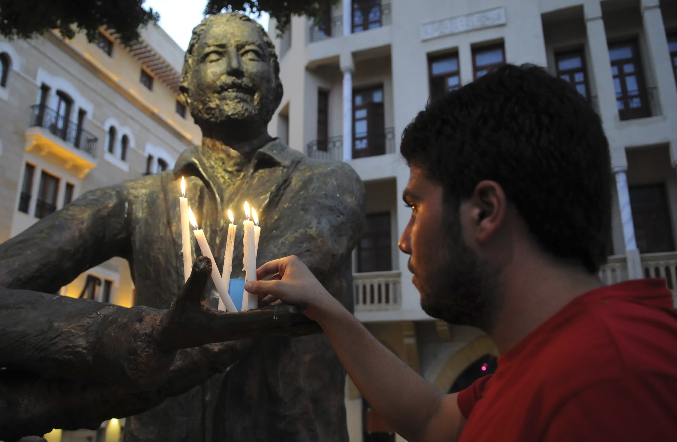 אזרח לבנוני מדליק נר על פסלו של העיתונאי סמיר קסיר, 31 ביולי 2011 (צילום: (AP Photo/Ahmad Omar)