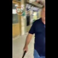 אדם מאיים באקדח על מפגין, צילום מסך מסרטון של "חדשות בזמן"