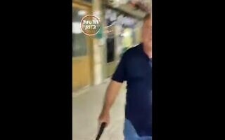 אדם מאיים באקדח על מפגין, צילום מסך מסרטון של “חדשות בזמן” אדם מאיים באקדח על מפגין, צילום מסך מסרטון של “חדשות בזמן”