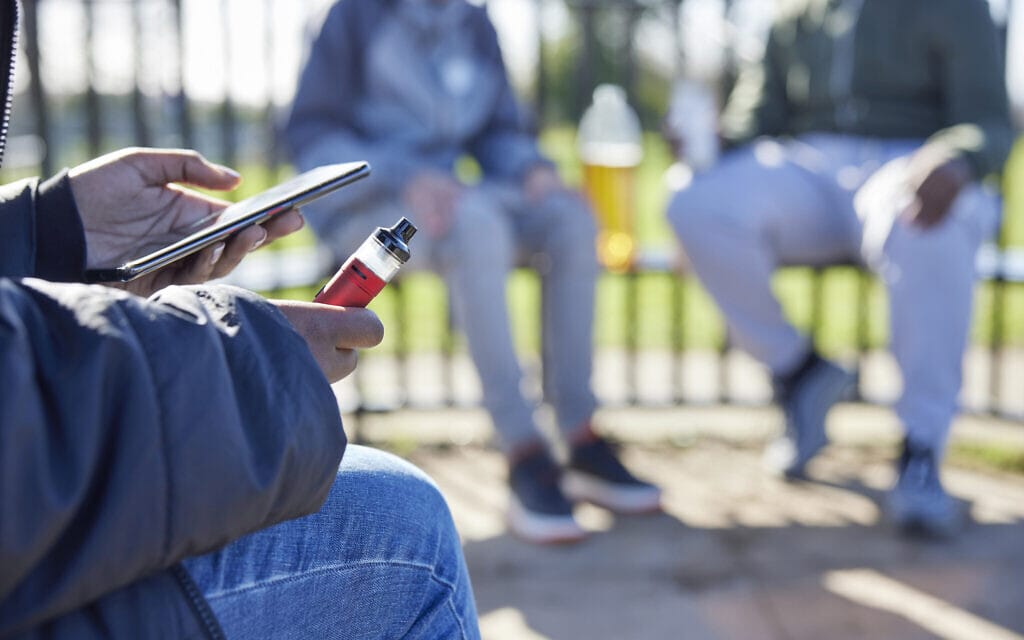 אילוסטרציה: בני נוער מעשנים סיגריות אלקטרוניות בפארק (צילום: iStock)