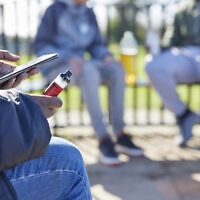 אילוסטרציה: בני נוער מעשנים סיגריות אלקטרוניות בפארק