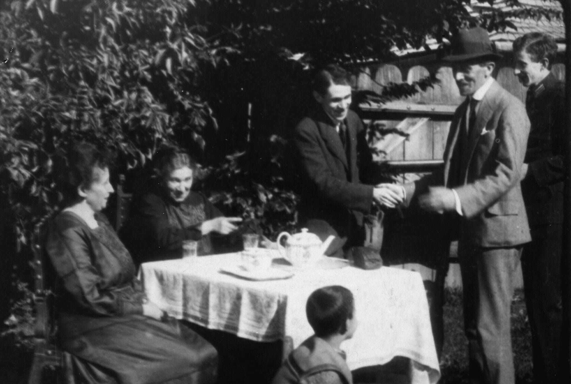 ברונו שולץ (עומד במרכז) עם אימו הנרייטה (יושבת ליד שולץ) ובני משפחה נוספים בחצר ביתם בדרוהוביץ&#8217;, סביבות 1930 (צילום: המוזיאון לספרות ע&quot;ש אדם מיצקביץ&#039;, ורשה)