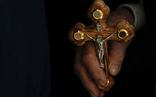 נוצרי אורתודוקסי מחזיק צלב בכנסיית הקבר, ירושלים, 14 באפריל 2023