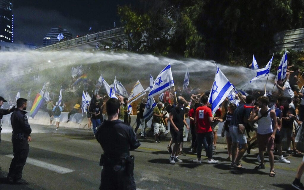 כוח משטרתי מתיז מים על מפגינים המוחים נגד המהפכה המשפטית בנתיבי איילון בתל אביב, 8 ביולי 2023 (צילום: Ohad Zwigenberg, AP)