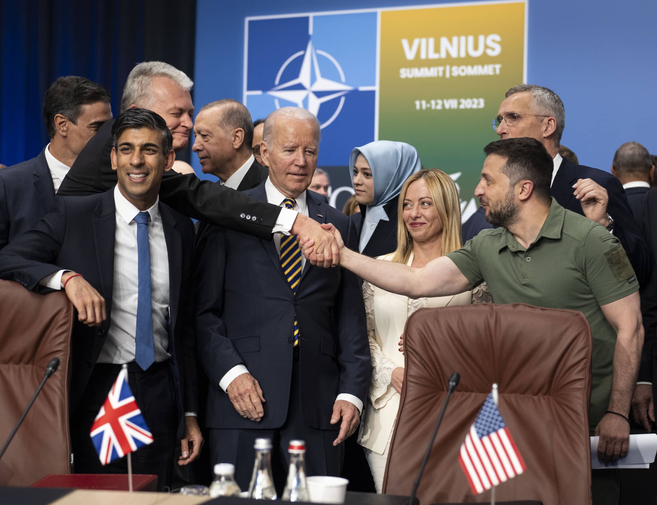 נשיא אוקראינה וולודימיר זלנסקי לוחץ את ידו של נשיא ליטא, המאחרת את פסגת נאט&quot;ו, עם מנהיגי העולם על הבמה &#8211; ביניהם נשיא ארה&quot;ב ג&#039;ו ביידן וראש ממשלת בריטניה רישי סונאק, 12 ביולי 2023 (צילום: Doug Mills/Pool via AP)