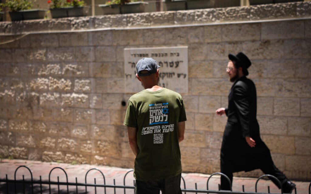 מפגין מטעם &quot;אחים לנשק&quot; מנסה לשוחח עם חרדי באזור לשכת הגיוס בירושלים, 17 ביולי 2023 (צילום: Chaim Goldberg/Flash90)