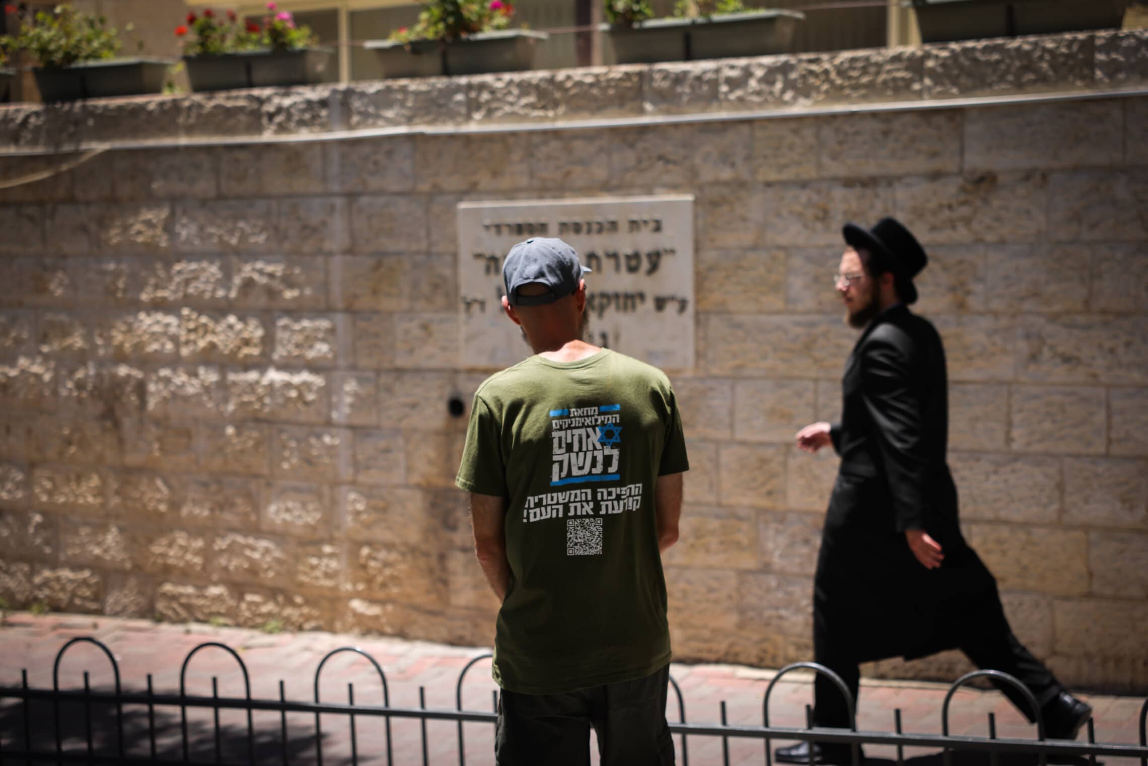 מפגין מטעם &#8220;אחים לנשק&#8221; מנסה לשוחח עם חרדי באזור לשכת הגיוס בירושלים, 17 ביולי 2023 (צילום: Chaim Goldberg/Flash90)