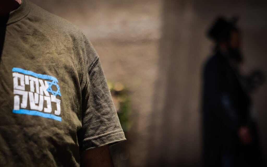 מפגין עם חולצה של "אחים לנשק" לצד חרדי באזור לשכת הגיוס בירושלים, 17 ביולי 2023 (צילום: חיים גולדברג/פלאש90)