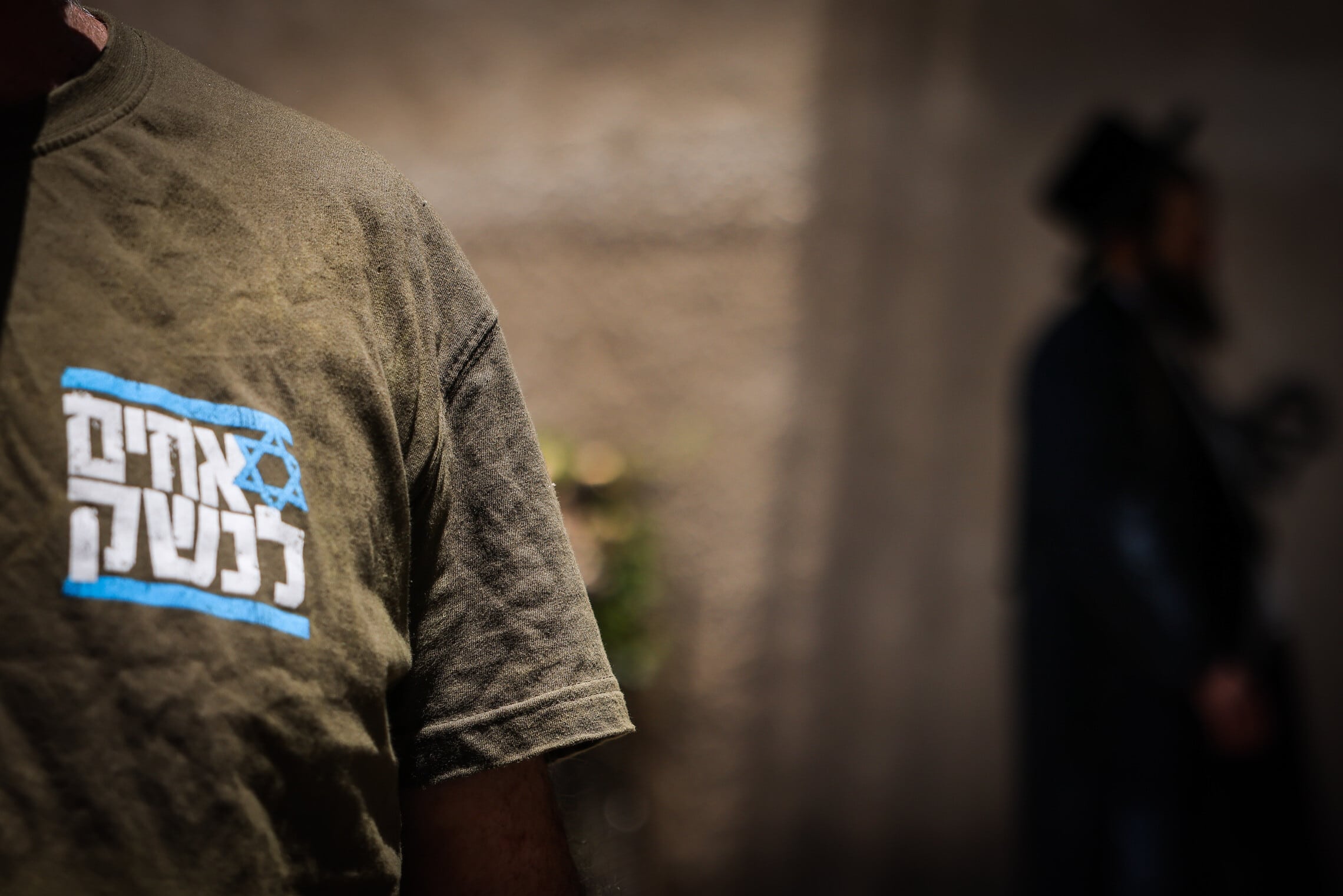 מפגין עם חולצה של "אחים לנשק" לצד חרדי באזור לשכת הגיוס בירושלים, 17 ביולי 2023 (צילום: חיים גולדברג/פלאש90)