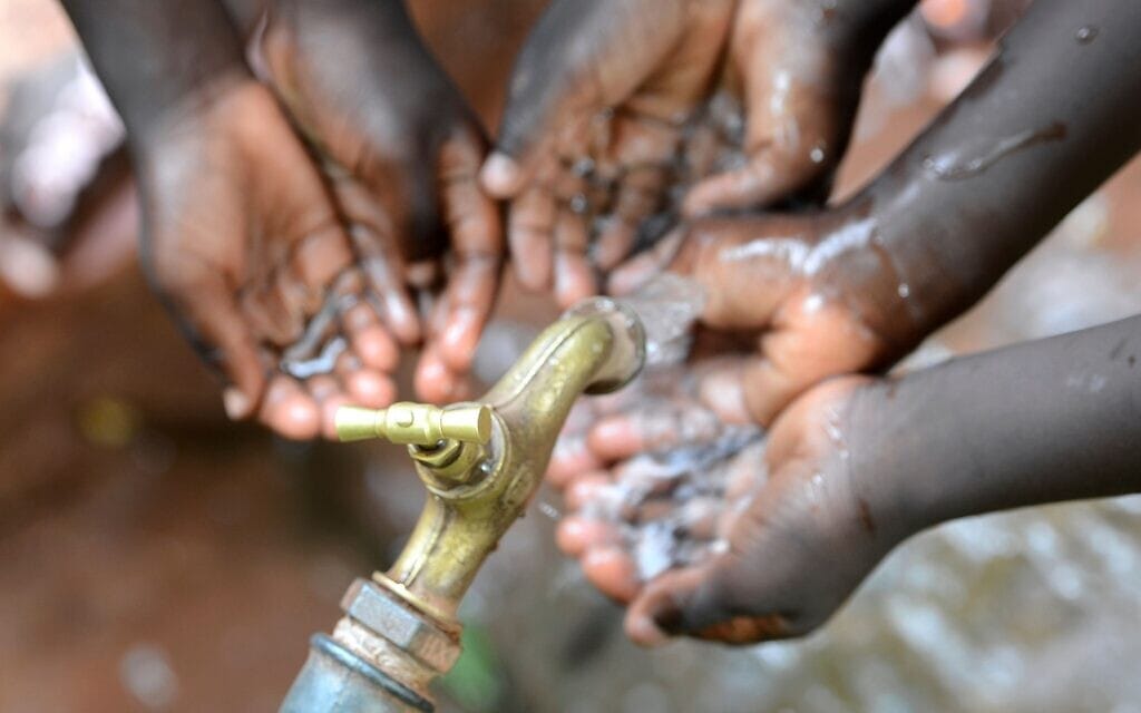 אילוסטרציה: ידיים של ילדים אפריקאים מתחת לברז מים (צילום: borgogniels; iStock by Getty Images)