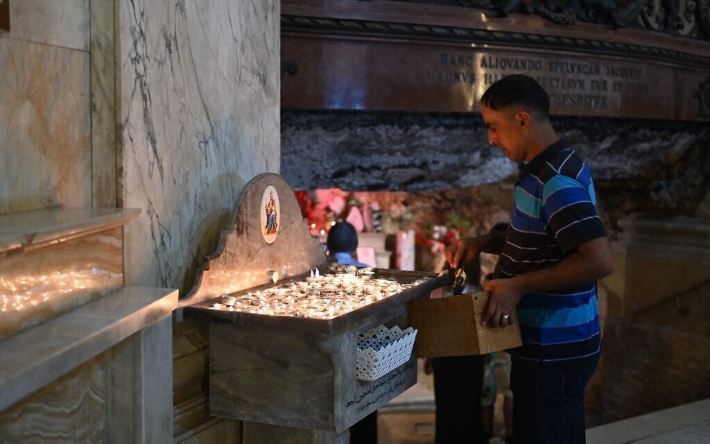 חבר בכנסיית סטלה מאריס בחיפה מסיר שעווה שנזלה מהנרות שהדליקו מאמינים, 20 ביולי 2023 (צילום: כנען לידור)