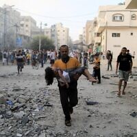 גבר פלסטיני מחזיק ילדה פצועה אחרי תקיפה ישראלית בעזה, 14 באוקטובר 2023