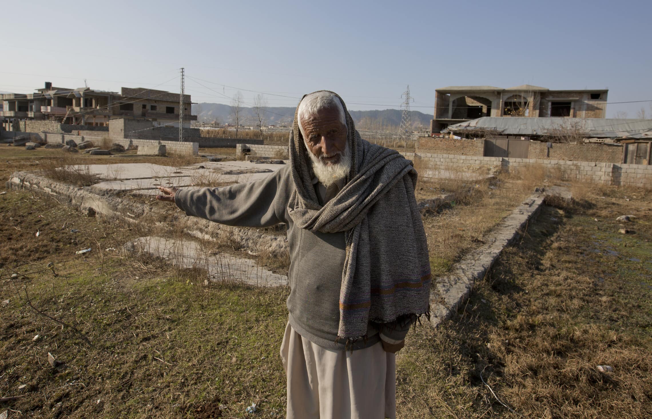 זאין מוחמד, שומר לשעבר שעבד עבור אוסמה בן לאדן, מצביע על שאריות ביתו של בן לאדן באבוטאבאד, ינואר 2018 (צילום: AP Photo/B.K. Bangash)