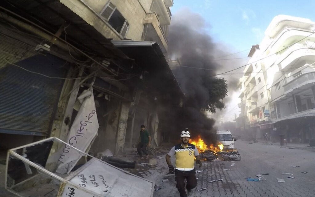 איש ארגון הקסדות הלבנות בדרכו לאתר שנפגע מפגז בפאתי ג'סר א-שורור שבסוריה, 5 באוקטובר 2023 (צילום: Syrian Civil Defense White Helmets via AP)