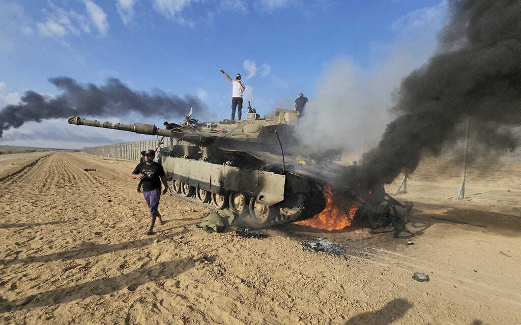 פלסטינים חוגגים על טנק ישראלי הרוס, 7 באוקטובר 2023 (צילום: AP Photo) פלסטינים חוגגים על טנק ישראלי הרוס, 7 באוקטובר 2023 (צילום: AP Photo)