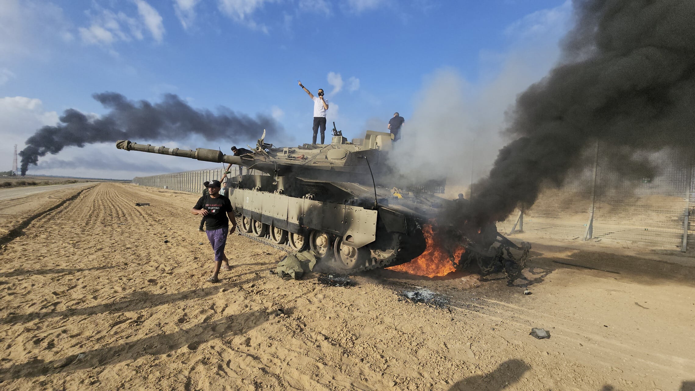 פלסטינים חוגגים על טנק ישראלי הרוס, 7 באוקטובר 2023 (צילום: AP)