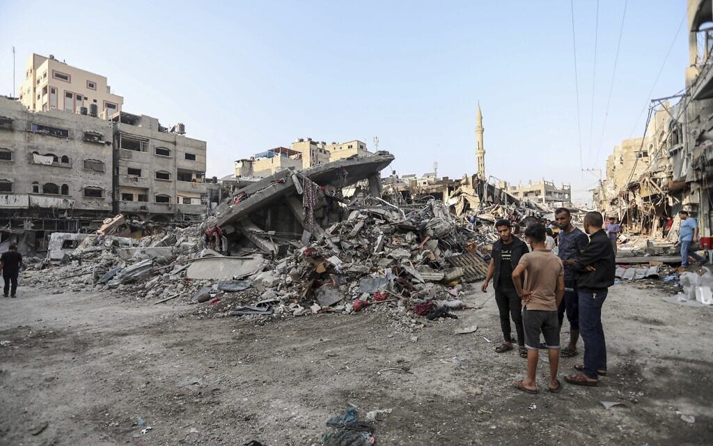 פלסטינים ליד הריסות מבנים לאחר הפצצה ישראלית. 28 באוקטובר 2023 (צילום: AP Photo/Abed Khaled)