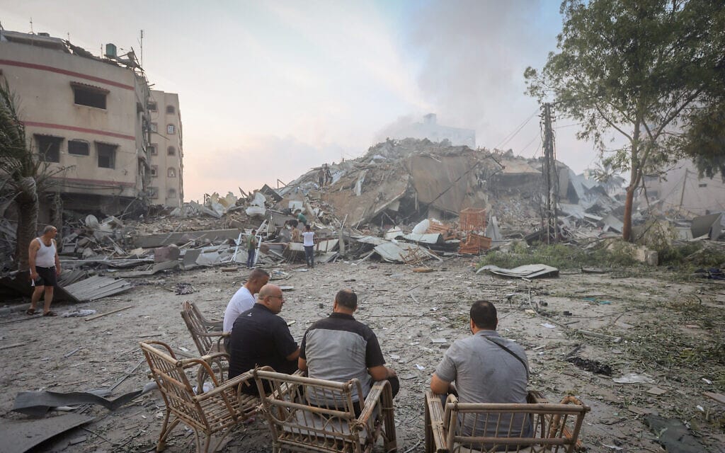 פלסטינים יושבים מול בית שנהרס בתקיפת חיל האוויר בעזה, 8 באוקטובר 2023 (צילום: Atia Mohammed/Flash90)