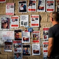 אדם מביט על קיר המציג את בני הערובה בעזה, תל אביב, 18 באוקטובר 2023 (צילום: Chaim Goldberg/Flash90)