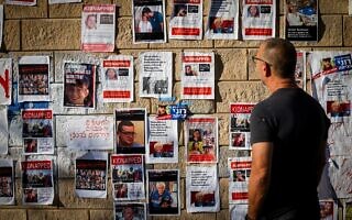 אדם מביט על קיר המציג את בני הערובה בעזה, תל אביב, 18 באוקטובר 2023 (צילום: Chaim Goldberg/Flash90) אדם מביט על קיר המציג את בני הערובה בעזה, תל אביב, 18 באוקטובר 2023 (צילום: Chaim Goldberg/Flash90)