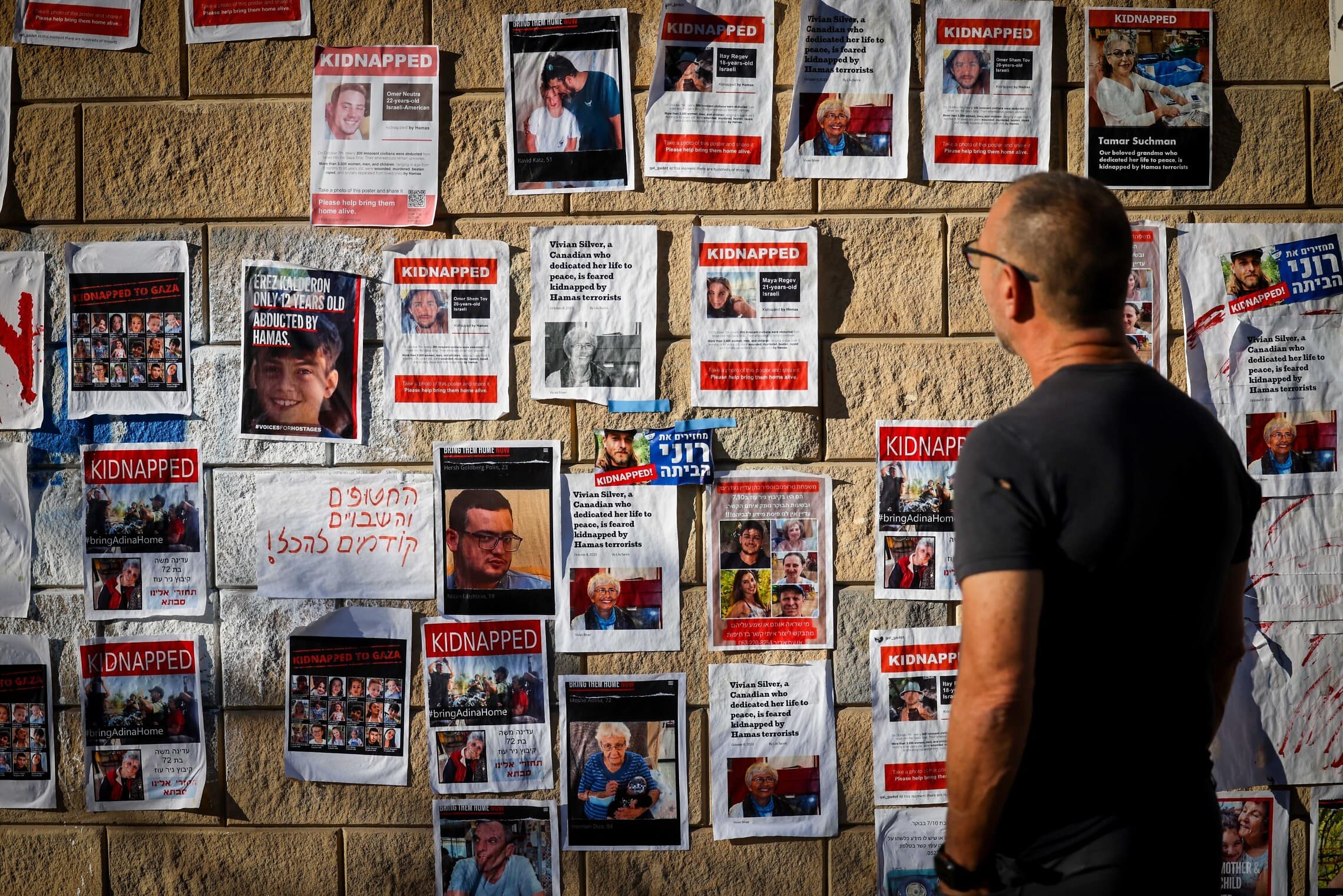 אדם מביט על קיר המציג את בני הערובה בעזה, תל אביב, 18 באוקטובר 2023 (צילום: Chaim Goldberg/Flash90)