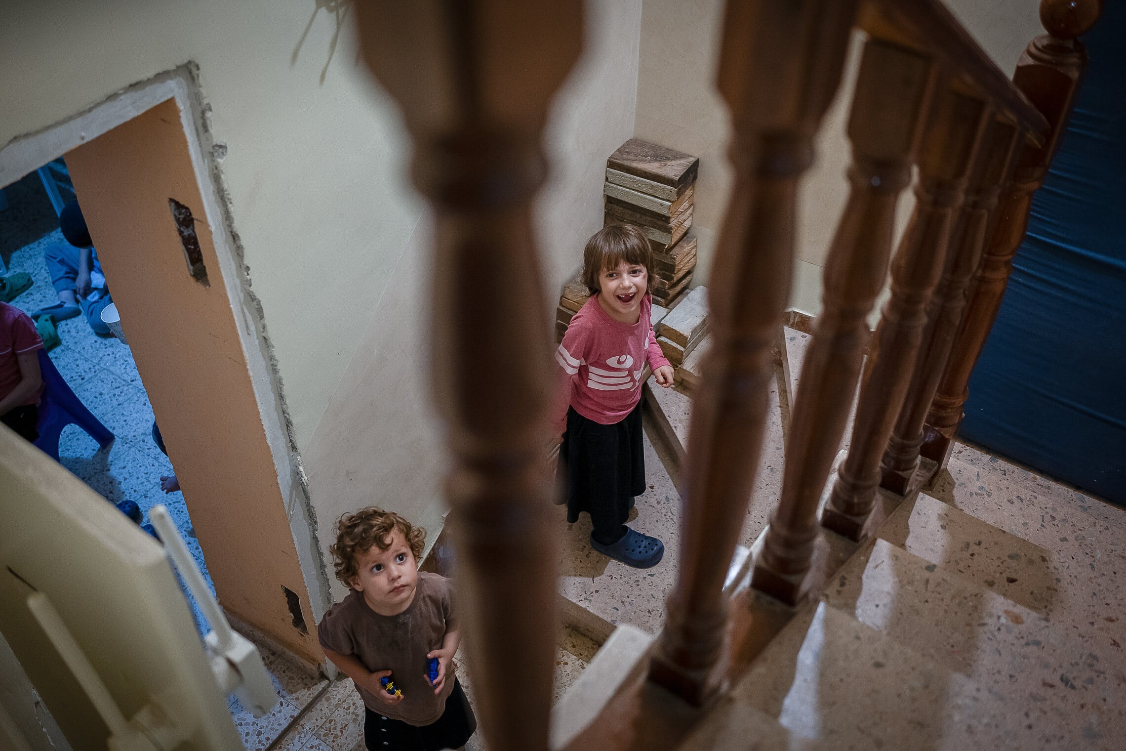 .ילדים שביתם נפגע מפגיעת רקטה מלבנון עומדים ליד מקלט בקריית שמונה, 23 באוקטובר 2023 (צילום: ארז בן שמעון, פלאש 90)