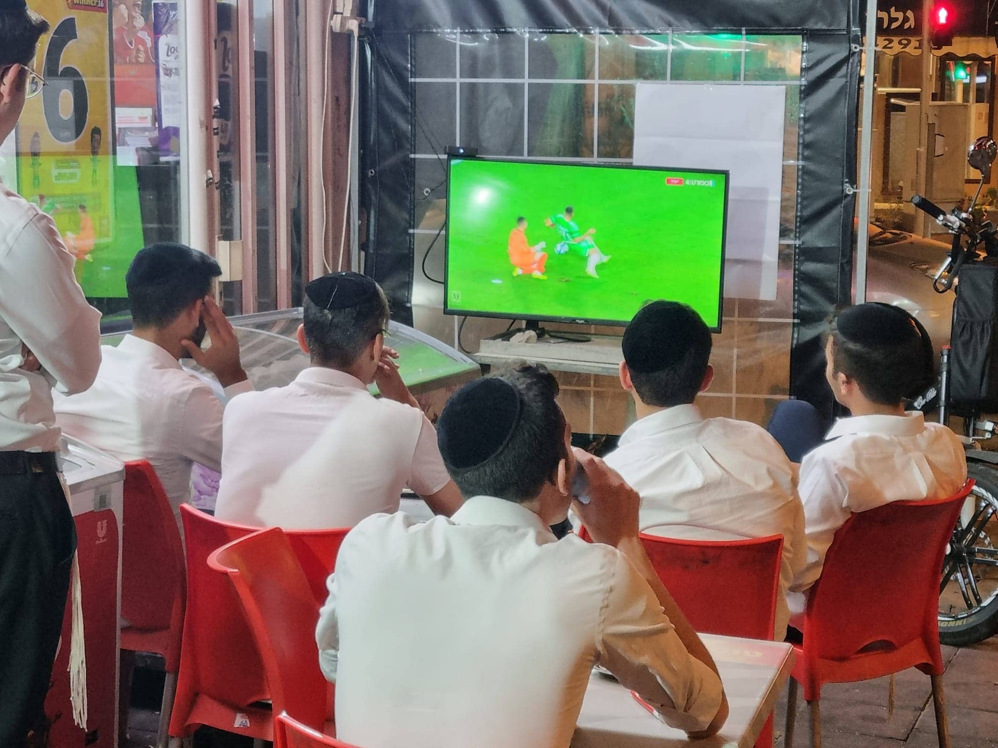 צעירים חרדים צופים במשחק כדורגל בפיצוציה רמת גן (צילום: תני גולדשטיין)