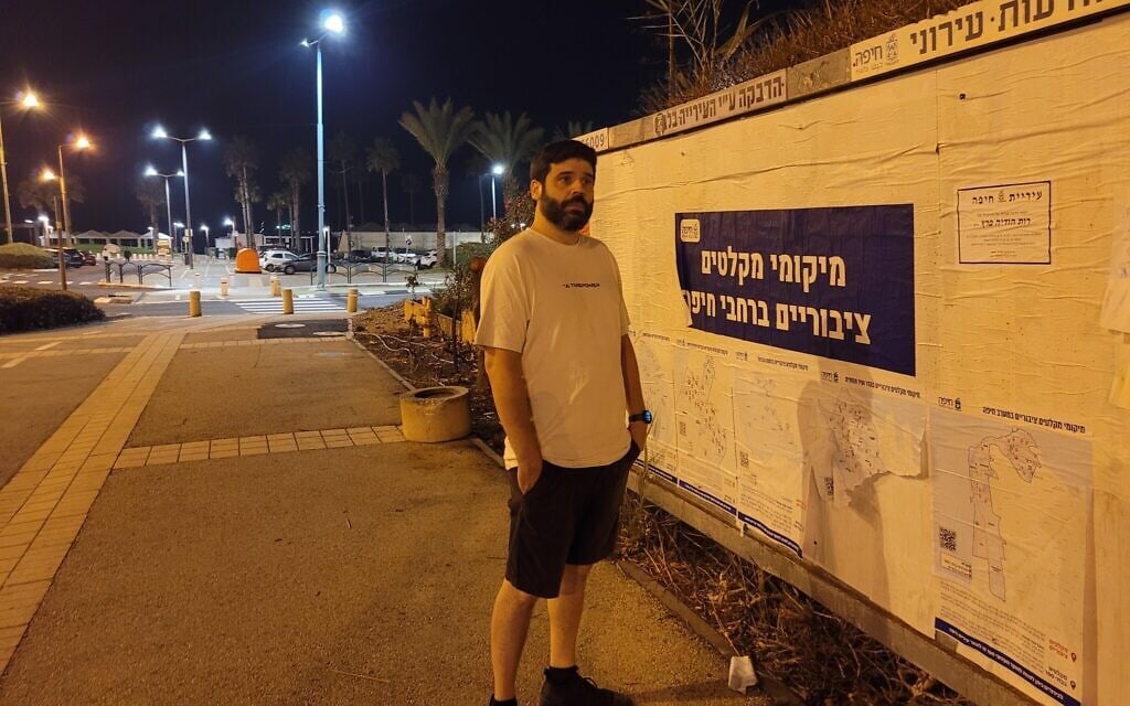 גבר בוחן כרזה המציגה את מיקומי המקלטים בחיפה, 17 בנובמבר 2023 (צילום: כנען לידור)