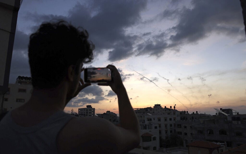 גבר מצלם בטלפון הנייד את ירי הרקטות מרצועת עזה לעבר ישראל, 7 באוקטובר 2023 (צילום: MOHAMMED ABED / AFP)