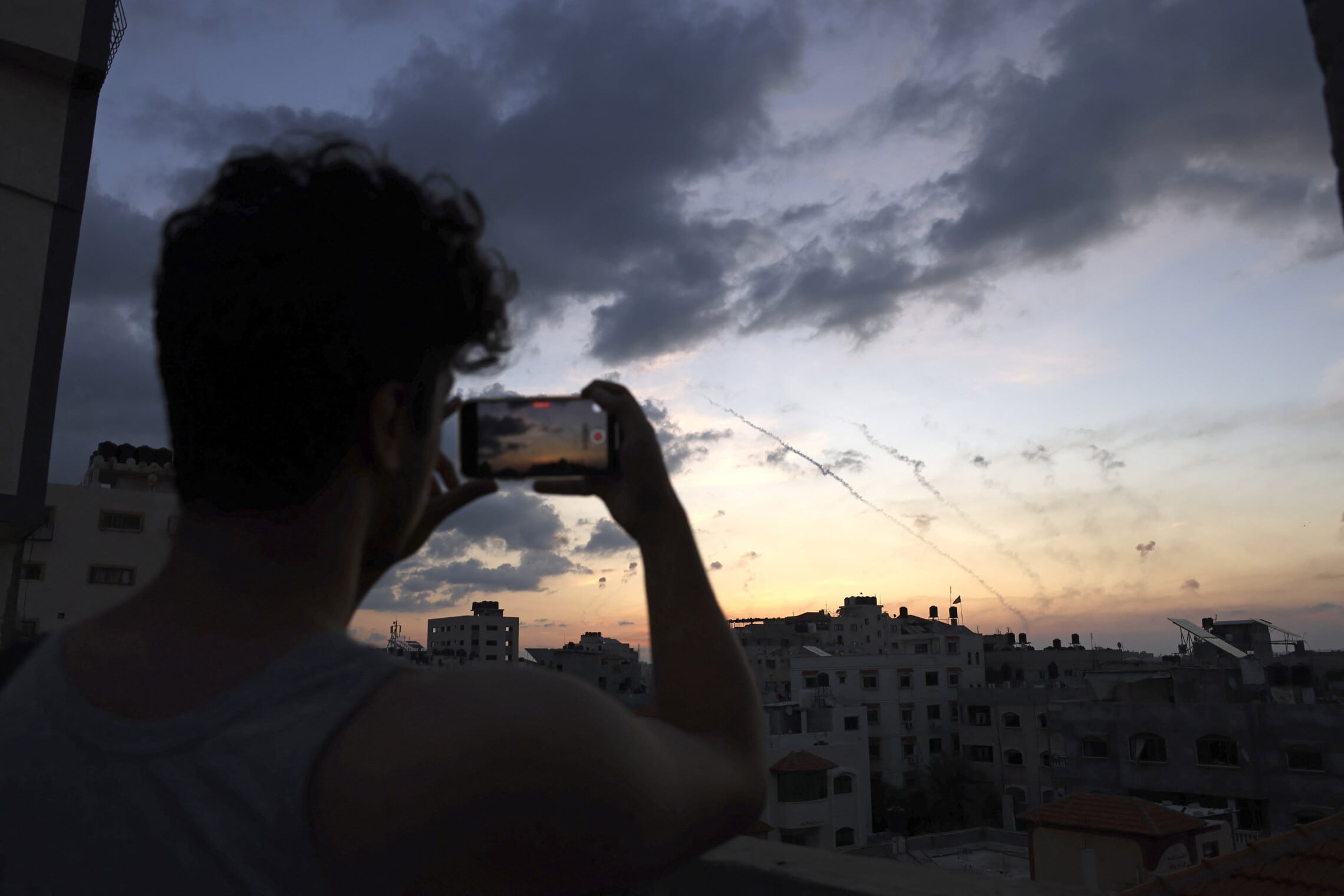 גבר מצלם בטלפון הנייד את ירי הרקטות מרצועת עזה לעבר ישראל, 7 באוקטובר 2023 (צילום: MOHAMMED ABED / AFP)