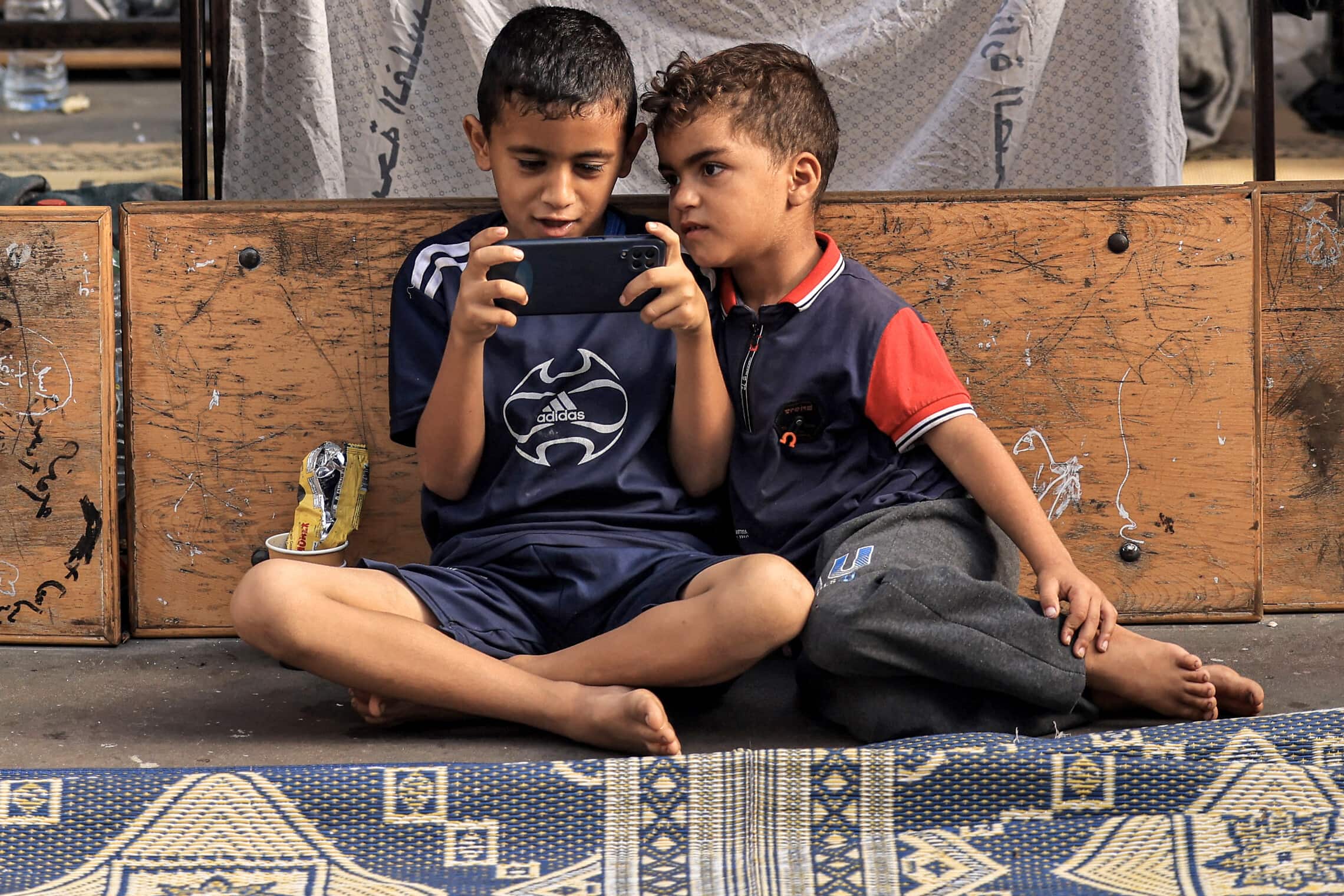 ילדים פלסטינים משחקים בטלפון הסלולרי בחאן יונס, 25 באוקוטבר 2023 (צילום: MAHMUD HAMS / AFP)
