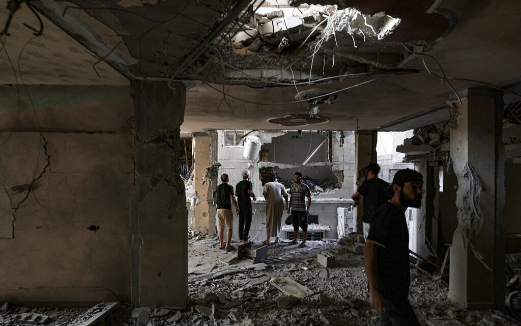פלסטינים בחאן יונס בוחנים את הנזק שנגרם לבניין שנפגע בהפצצה ישראלית, 11 בנובמבר 2023 (צילום: Mahmud HAMS / AFP)