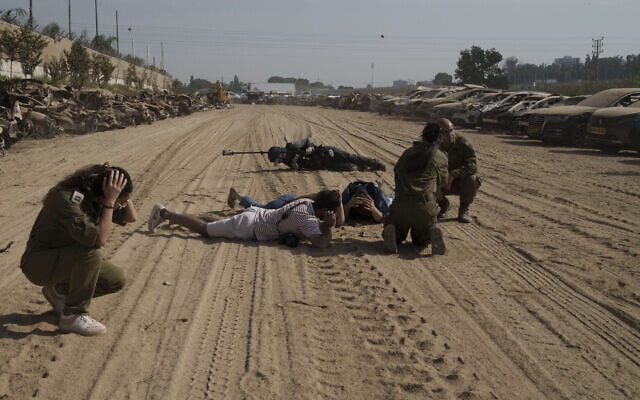 חיילים ועיתונאים נשכבים או יושבים על הקרקע, ליד נתיבות, בשעה שמופעלת אזעקה המתריעה מפני פגיעת טילים ורקטות, 5 בנובמבר 2023 (צילום: AP Photo / Leo Correa) חיילים ועיתונאים נשכבים או יושבים על הקרקע, ליד נתיבות, בשעה שמופעלת אזעקה המתריעה מפני פגיעת טילים ורקטות, 5 בנובמבר 2023 (צילום: AP Photo / Leo Correa)
