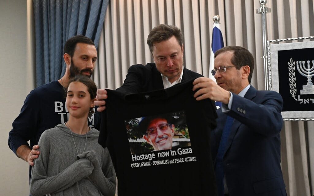 דניאל ולילו ליפשיץ מעניקים לאילון מאסק חולצה עם תמונה של סבם עודד ליפשיץ בקריאה לשחררו מהשבי בעזה, 27 בנובמבר 2023 (צילום: חיים צח/ לע״מ)