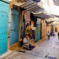 בעל חנות מזכרות יושב ברחוב כמעט ריק בעיר העתיקה בירושלים, 6 בנובמבר 2023 (צילום: ג'אנלוקה פקיאני)