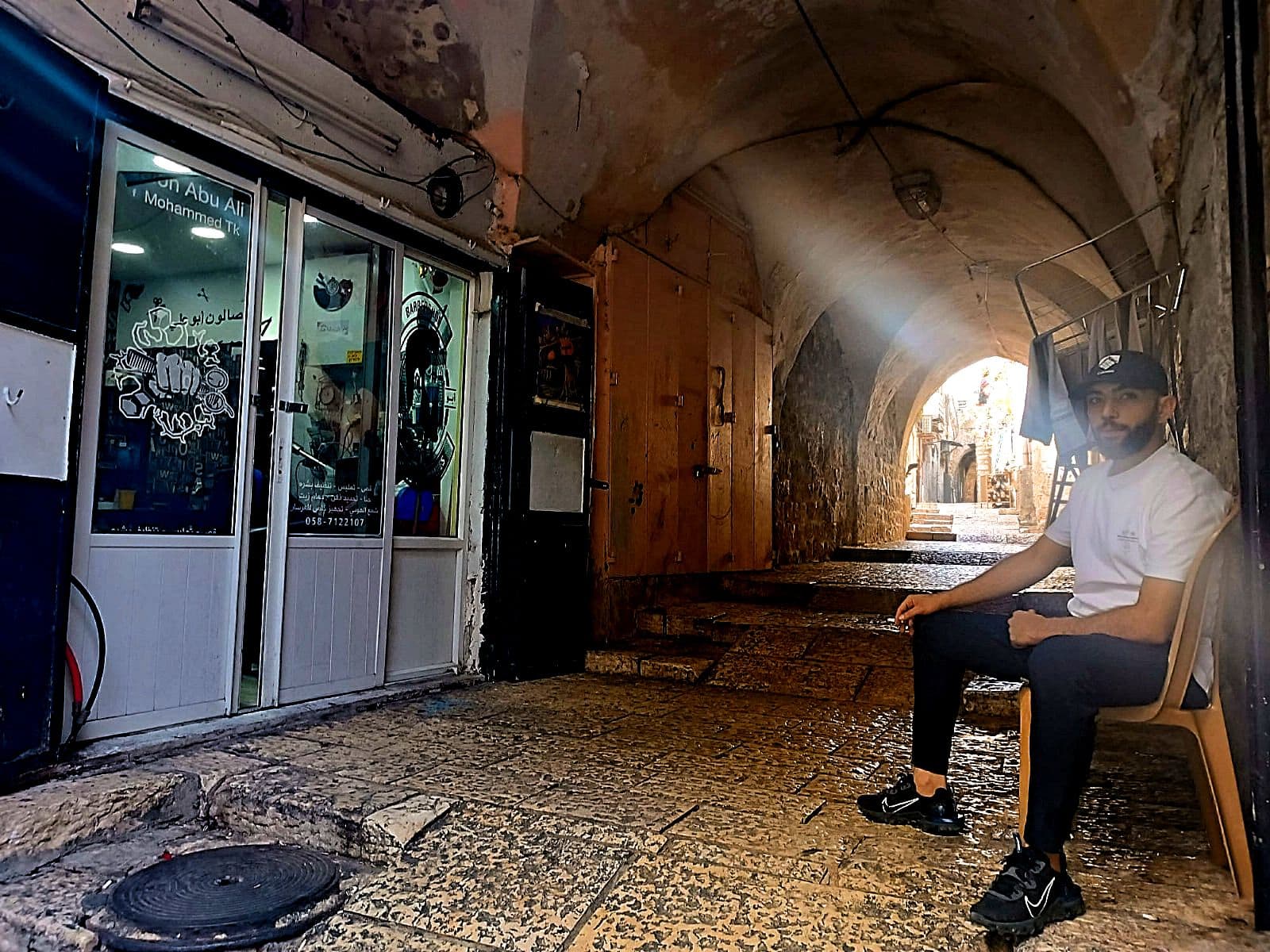 מוחמד אבו עלי, בעל מספרה ברובע המוסלמי בירושלים, יושב מחוץ למספרה, 6 בנובמבר 2023 (צילום: ג&#039;אנלוקה פקיאני)
