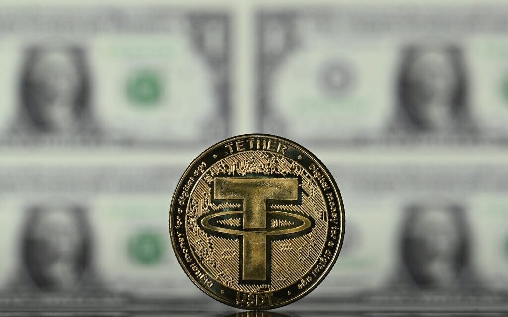אילוסטרציה: מטבע טתר מצופה זהב ודולר ושטרות דולר אמריקאי (צילום: Justin TALLIS / AFP)