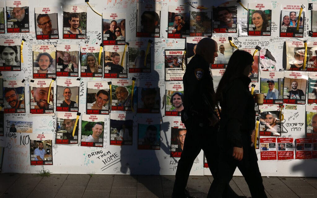 עוברי אורח חולפים על פני תמונותיהם של החטופים המוחזקים ברצועת עזה, 17 בדצמבר 2023 (צילום: Menahem Kahana / AFP)