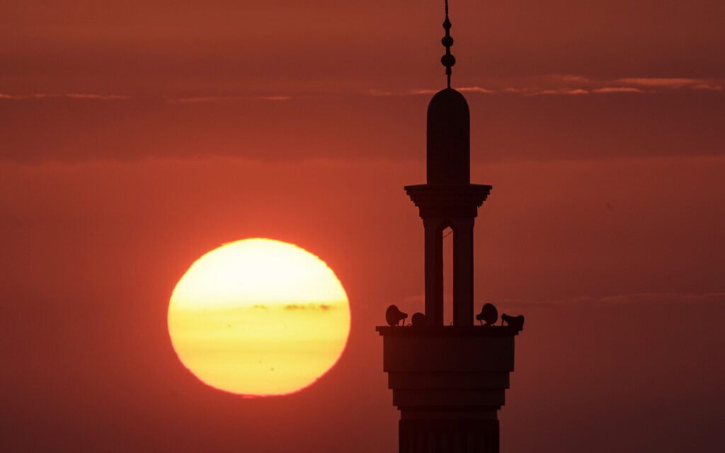 השמש שוקעת ברקע מסגד ברפיח ברצועת עזה, 25 בדצמבר 2023 (צילום: MAHMUD HAMS / AFP)