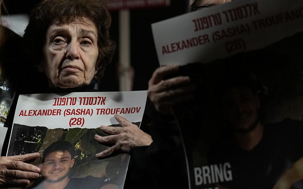 אירנה טטי, ששוחררה מהשבי ברצועת עזה, אוחזת בתמונתו של נכדה, סשה טרופנוב, שמוחזק בשבי, בהפגנה בתל אביב, 2 בדצמבר 2023 (צילום: AP Photo/Ariel Schalit)