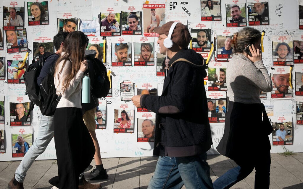 עוברי אורח בתל אביב חולפים על פני תמונות החטופים המוחזקים ברצועת עזה, 25 בדצמבר 2023 (צילום: מרים אלסטר/פלאש90)