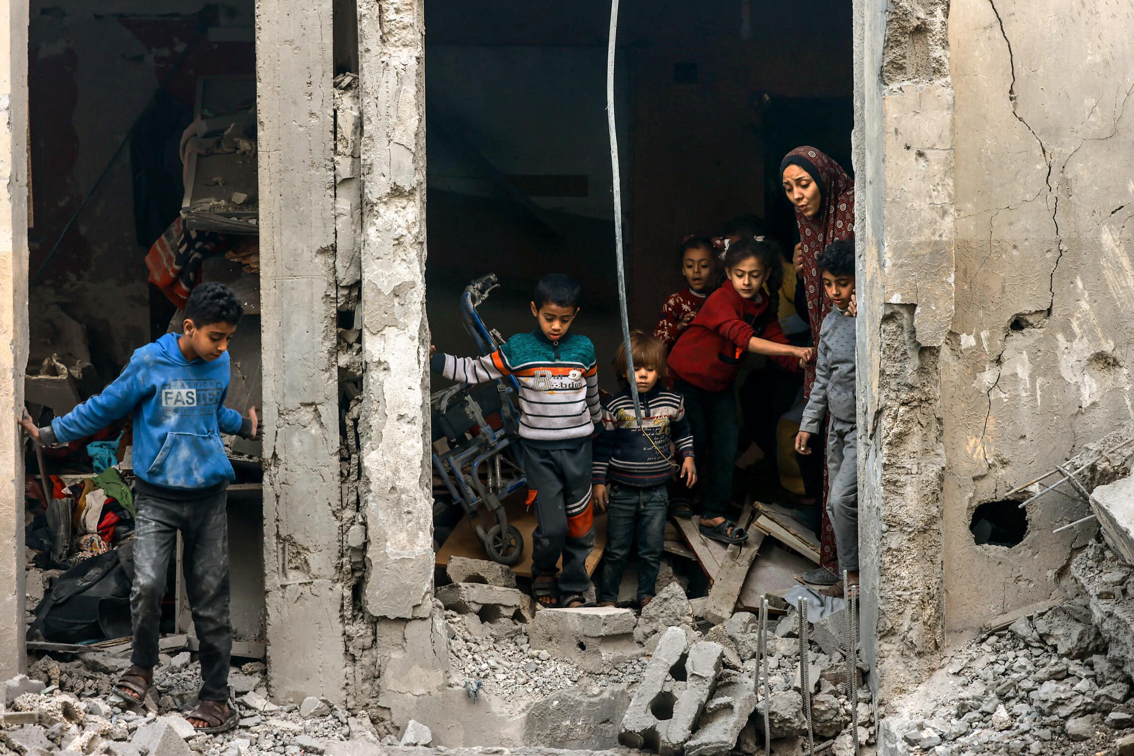 אישה פלסטינית וילדים בודקים את הריסות הבניין שהופצץ על ידי ישראל ברפיח, 22 בדצמבר 2023 (צילום: MOHAMMED ABED / AFP)