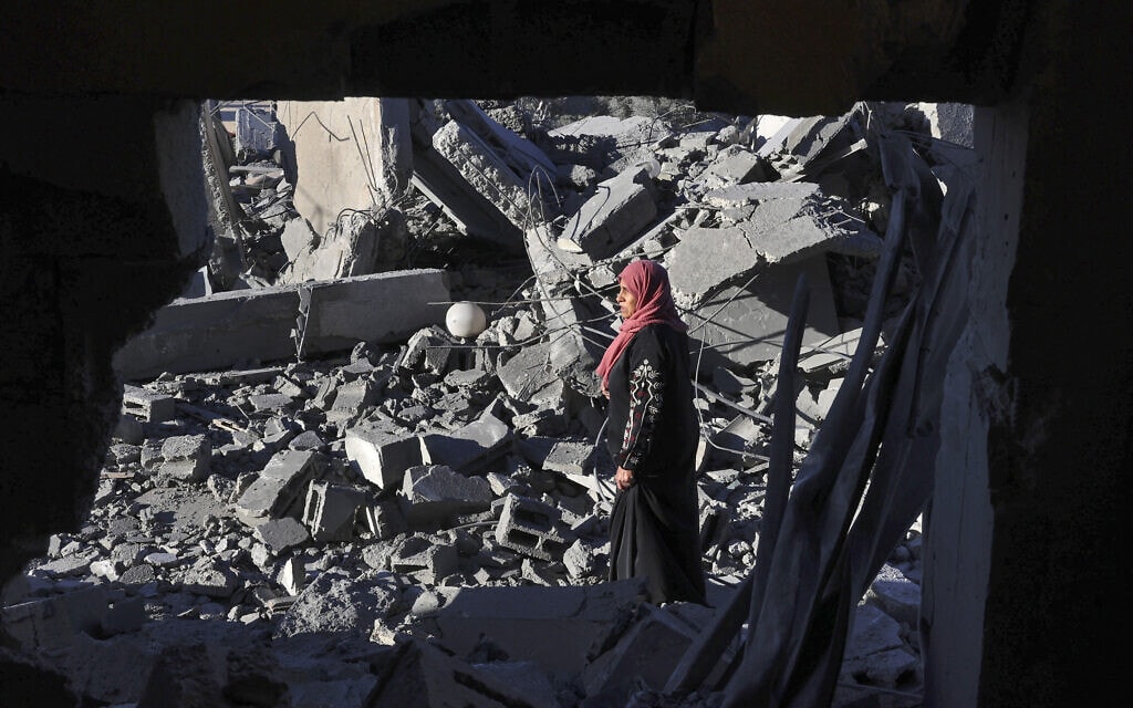 אישה פלסטינית עומדת בין ההריסות ברפיח, 13 בינואר 2024 (צילום: AFP)