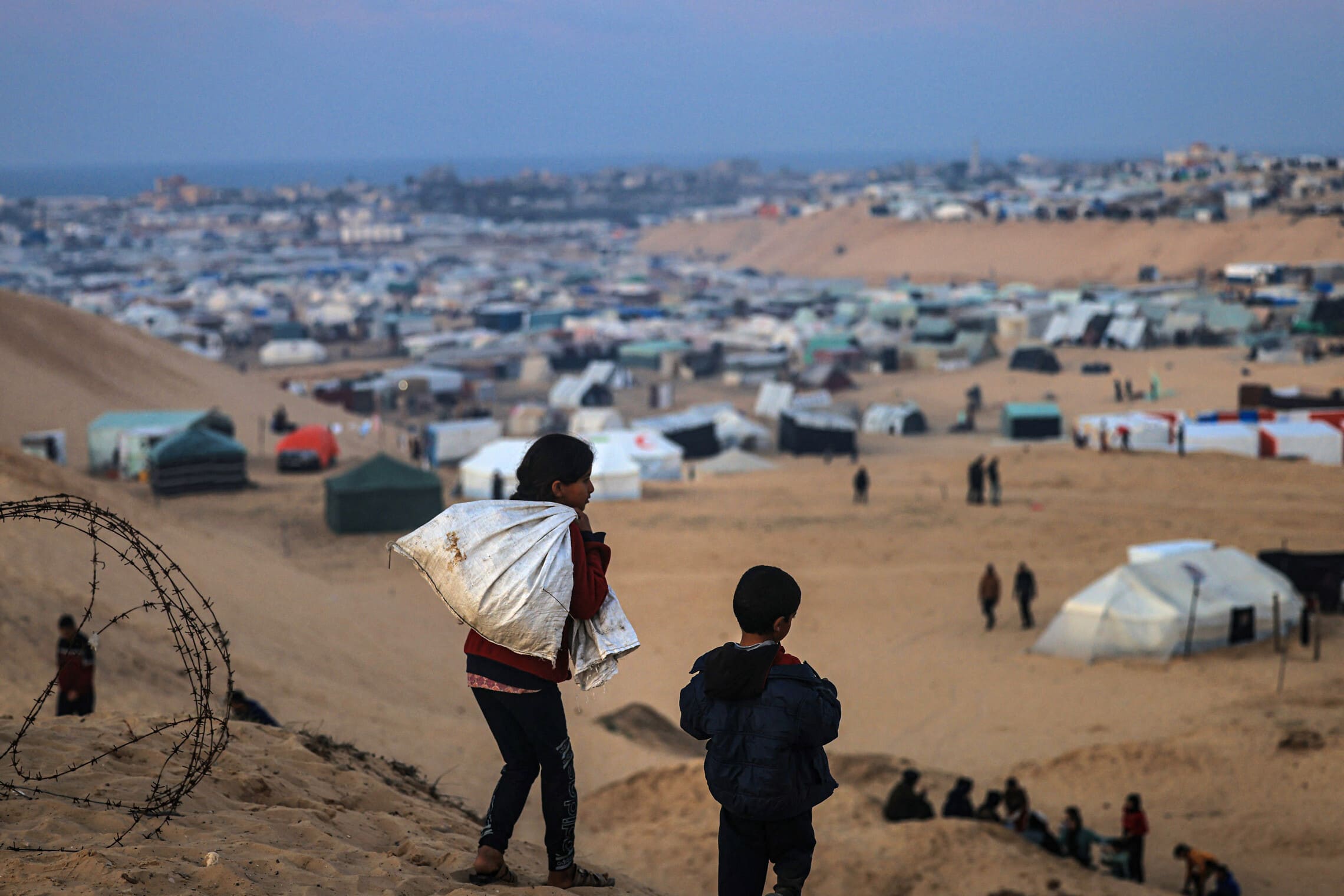 ילדים פלסטינים עקורים מול מחנה האוהלים המאולתר ברפיח, 19 בינואר 2024 (צילום: AFP)