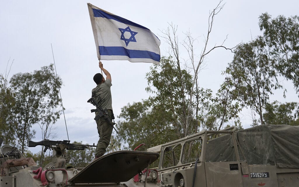 חייל מציב את דגל ישראל באזור התארגנות של כוחות צה"ל בכניסה לרצועת עזה. אילוסטרציה (צילום: AP Photo/Tsafrir Abayov)