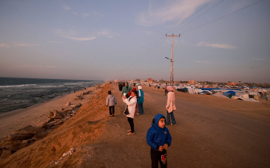 אנשים עומדים ברחוב בין חוף הים למחנה פליטים ברפיח, דרום רצועת עזה, 28 בפברואר 2024 (צילום: MOHAMMED ABED / AFP)